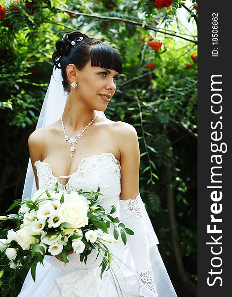Beautiful bride woman with guelder rose on the background outdoors
