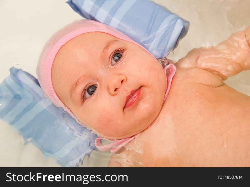 Cute baby swimming in a bath with self-made hat