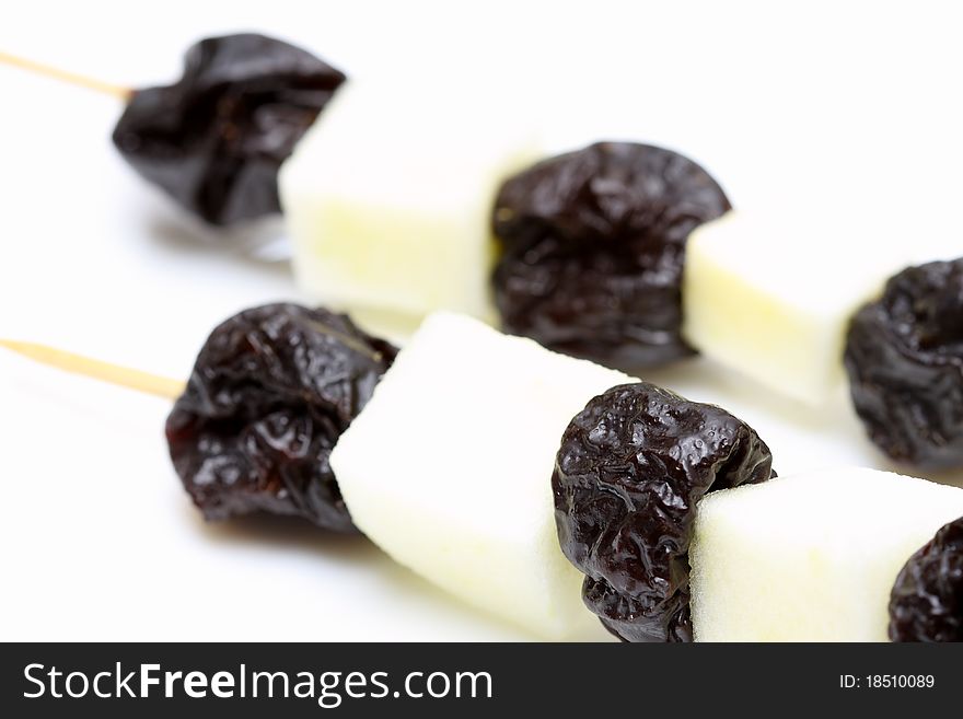 Prunes and apple on the stick on white background.