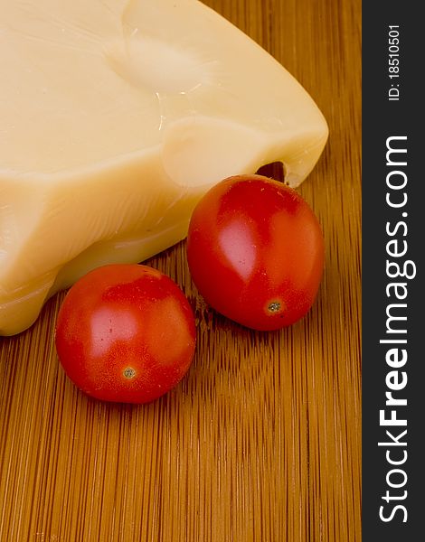 Swiss cheese slice and red tomato on a wood desk.