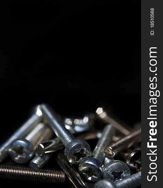 Metallic screws on black background, used as poster. Metallic screws on black background, used as poster