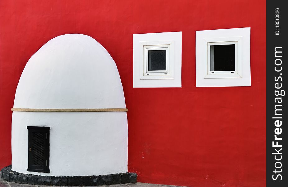 A Spanish porch, door, and two windows on a richly coloured red wall. A Spanish porch, door, and two windows on a richly coloured red wall