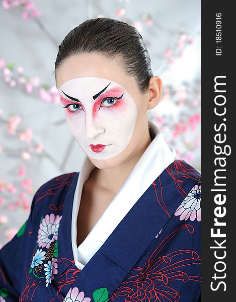 Artistic portrait of japan geisha woman with creative make-up near sakura tree