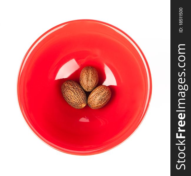 Red plate with nutmeg isolated on a white background