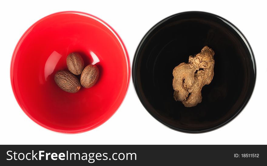 Red and black dish with spices, nutmeg and ginger,white background