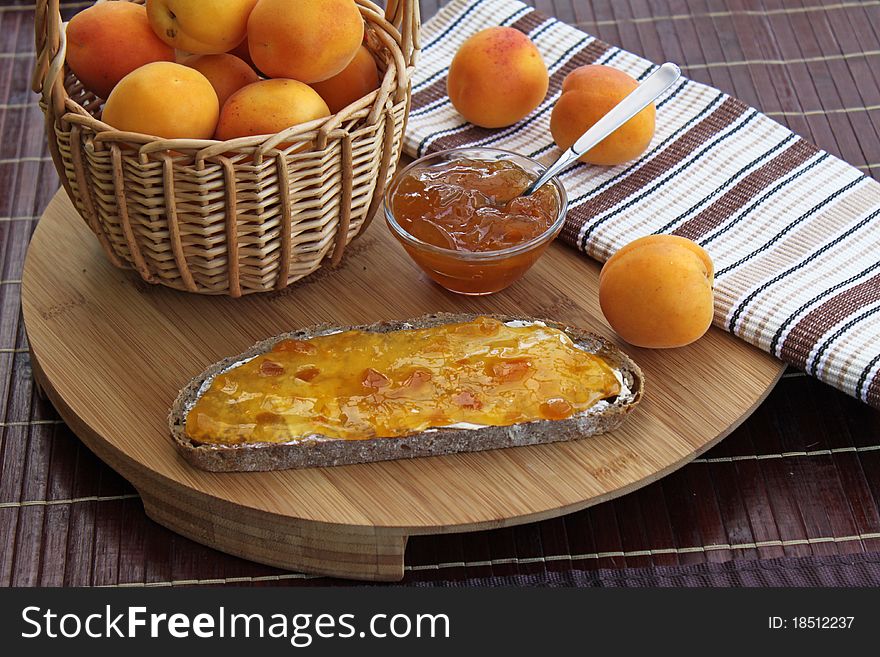 Wooden board with apricot jam and bread
