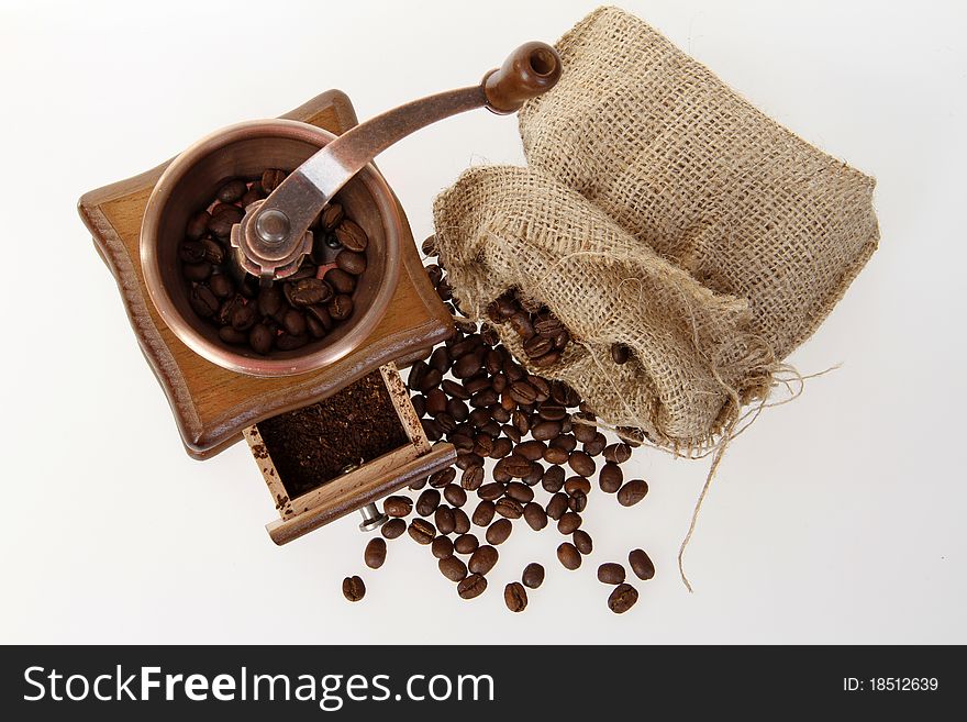 Coffee mill with burlap sack of roasted beans on the white background