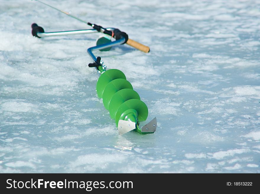 Green ice-drill on the blue ice - equipment for winter fishing