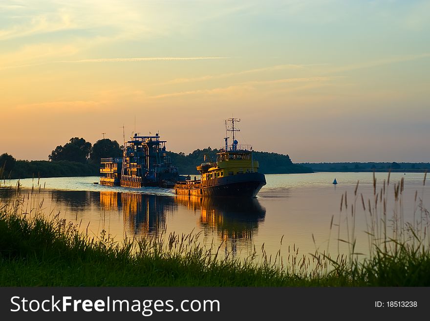 Steamers and barges glide across the water at sunset. Steamers and barges glide across the water at sunset