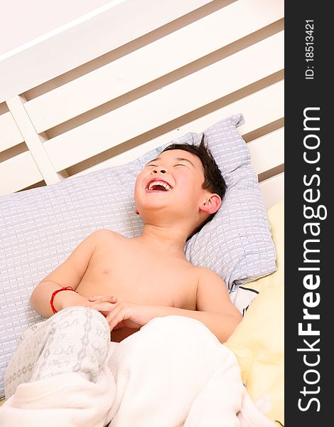 Picture of a little chinese boy laughing happily while lying on the bed. Picture of a little chinese boy laughing happily while lying on the bed