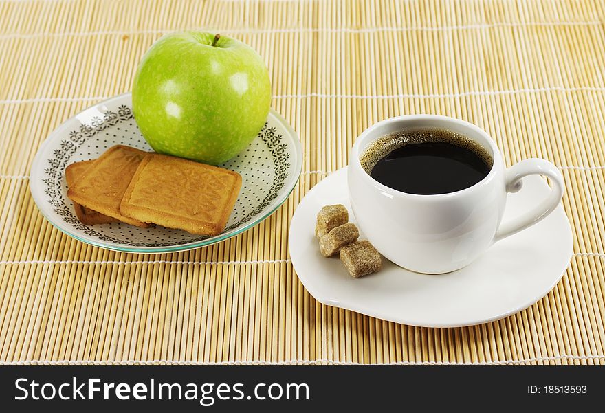 Cup of coffee, apple and biscuits on a plate stand on a napkin reed. Cup of coffee, apple and biscuits on a plate stand on a napkin reed