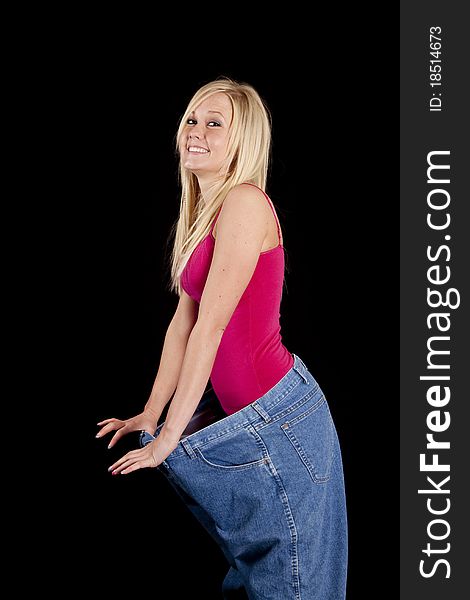 A woman with big pants is holding them out showing how much weight she has lost. A woman with big pants is holding them out showing how much weight she has lost.