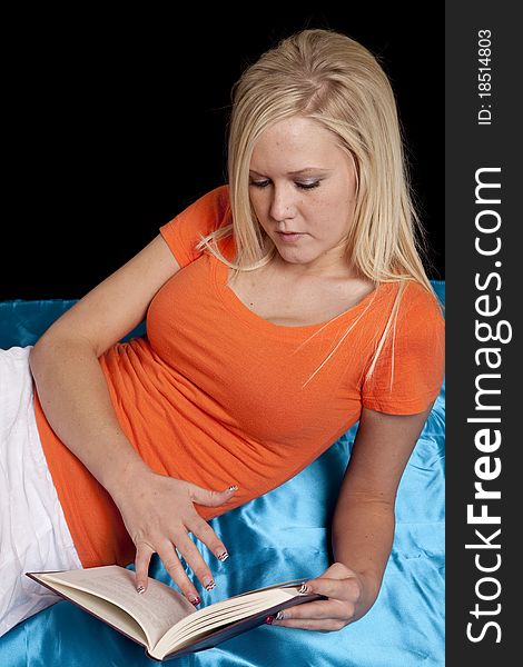 A woman in an orange shirt is reading a book. A woman in an orange shirt is reading a book.