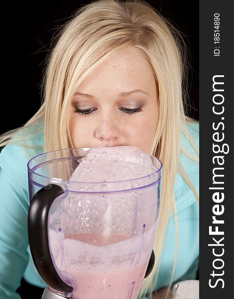 A woman is behind the blender looking into it. A woman is behind the blender looking into it.