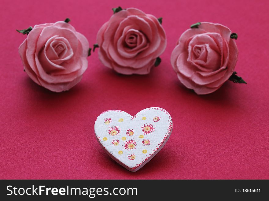 Patterned wooden heart and three pink roses. Patterned wooden heart and three pink roses