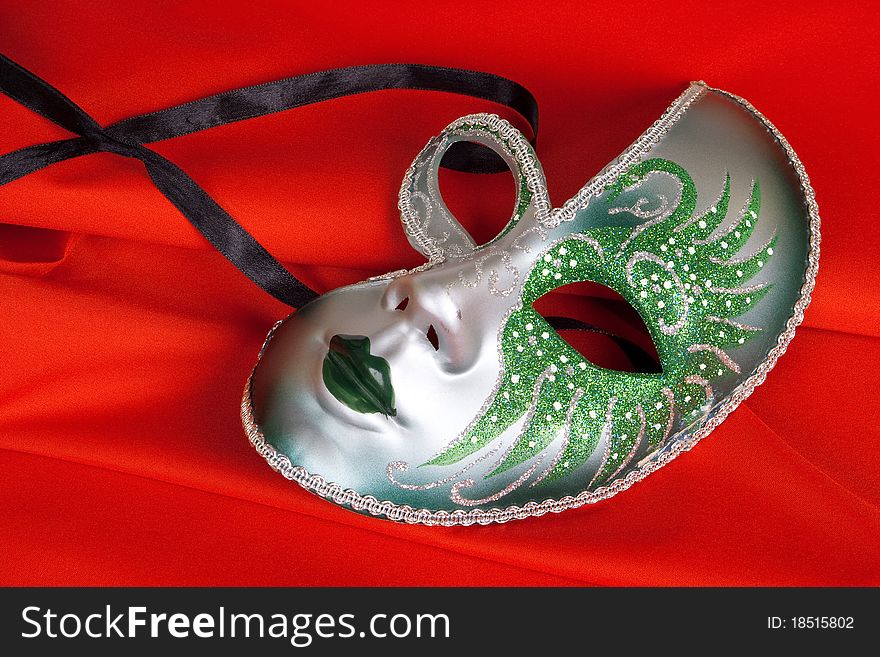 Carnival mask lying on a red, the tissue background