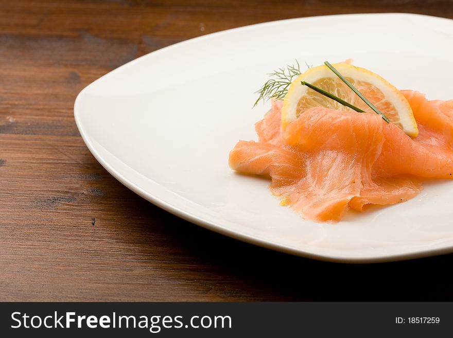 Photo of delicious smoked salmon with slice of lemon and fennel