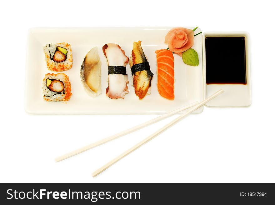 Variety of different types of sushi on the white plate over white background. Variety of different types of sushi on the white plate over white background