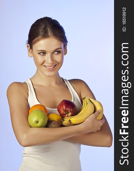 Young beautiful brunette is holding fruit on blue background isolated