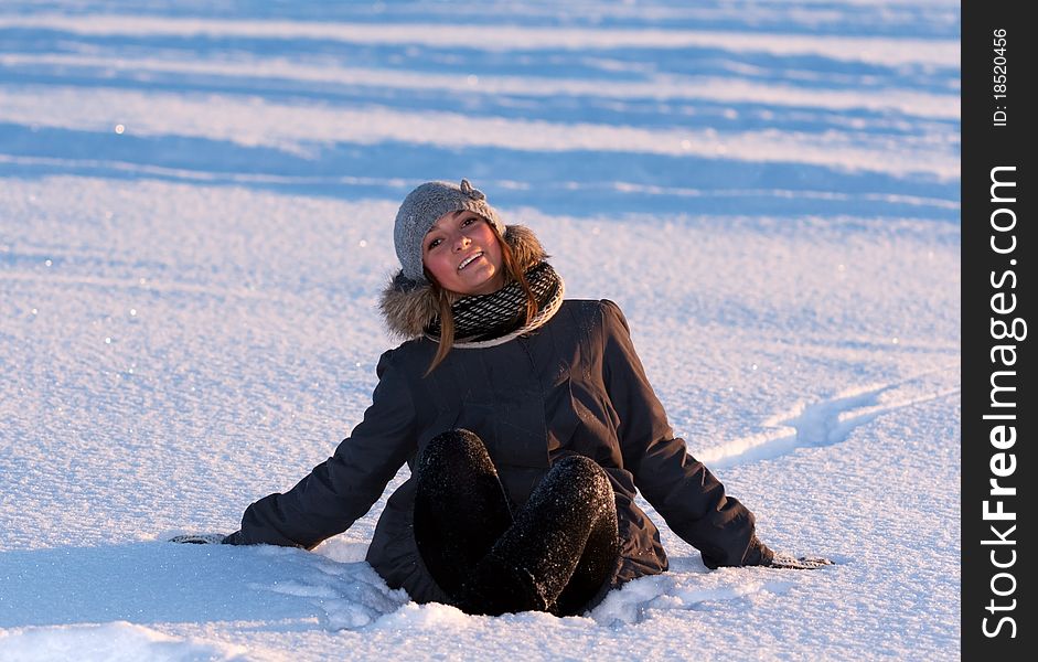 Beautiful young girl sitting in the snow