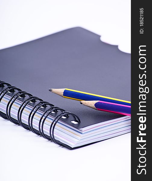 Notebook with a colored pencils on white background. Notebook with a colored pencils on white background