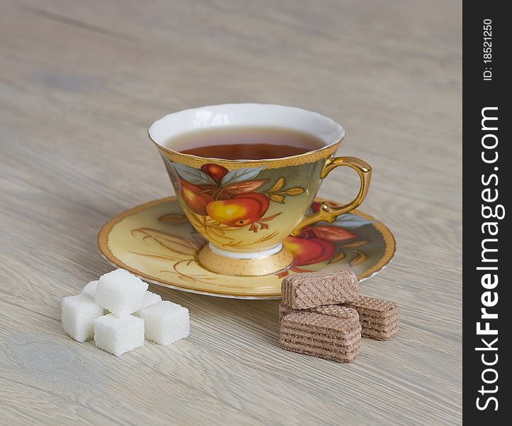 A cup of tea and sugar on a wooden table