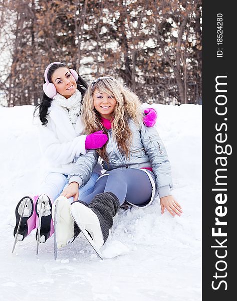 Two beautiful girls ice skating outdoor on a warm winter day (focus on the blond girl)