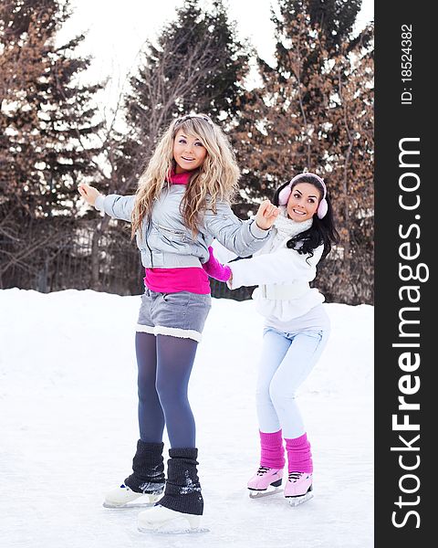 Two beautiful girls ice skating outdoor on a warm winter day (focus on the blond girl)