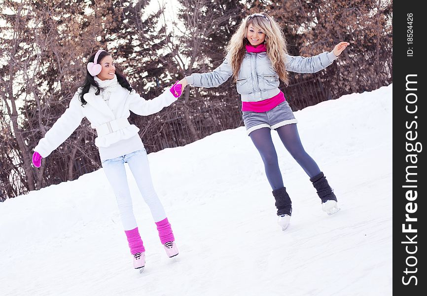 Two beautiful girls ice skating outdoor on a warm winter day (focus on the blond girl)