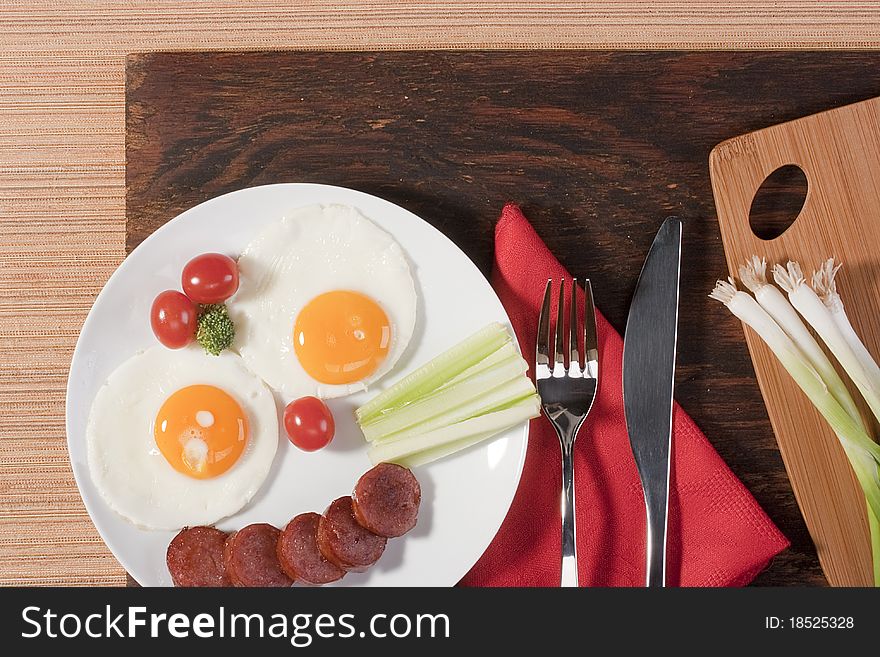 Fried eggs with fried sausage and vegetables.