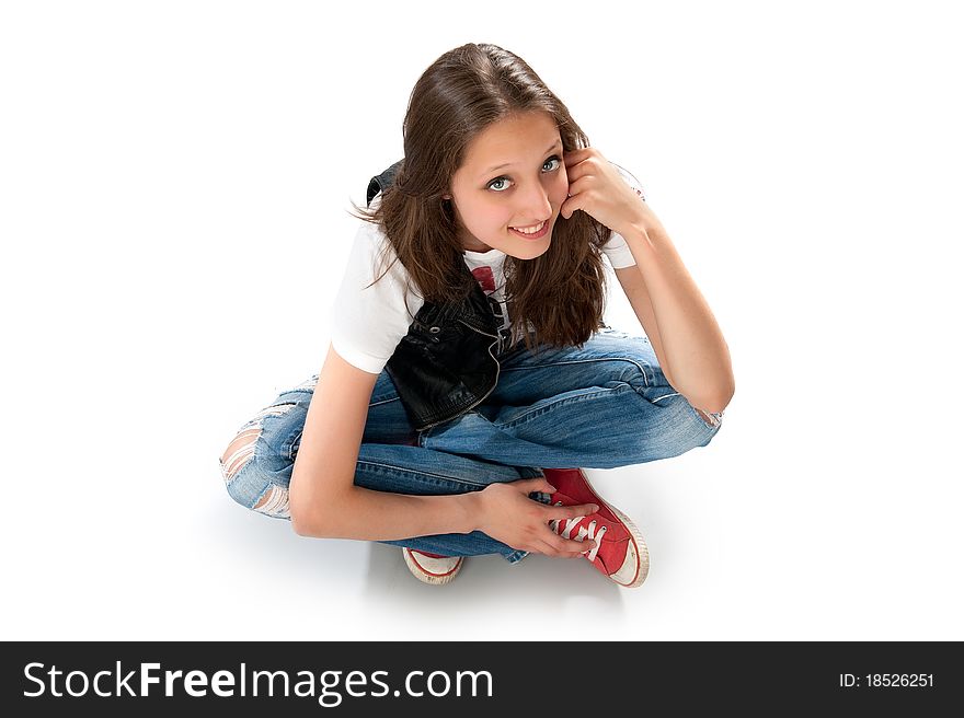 Teenage girl sitting on the floor. Isolated on white