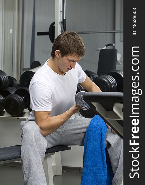Young man exercising with dumbbell in fitness club. Young man exercising with dumbbell in fitness club