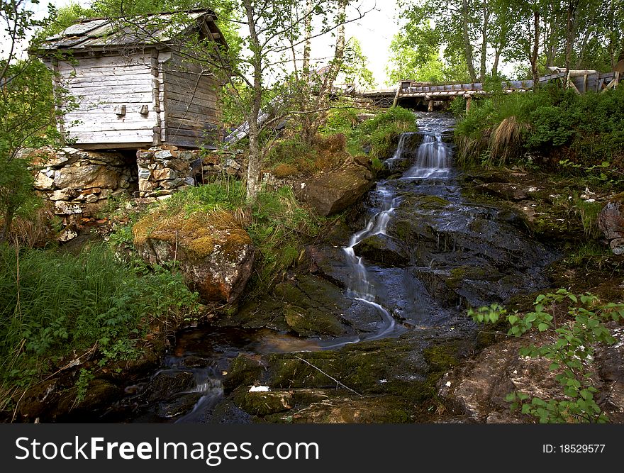 Wooden house near the waterfall in the forest