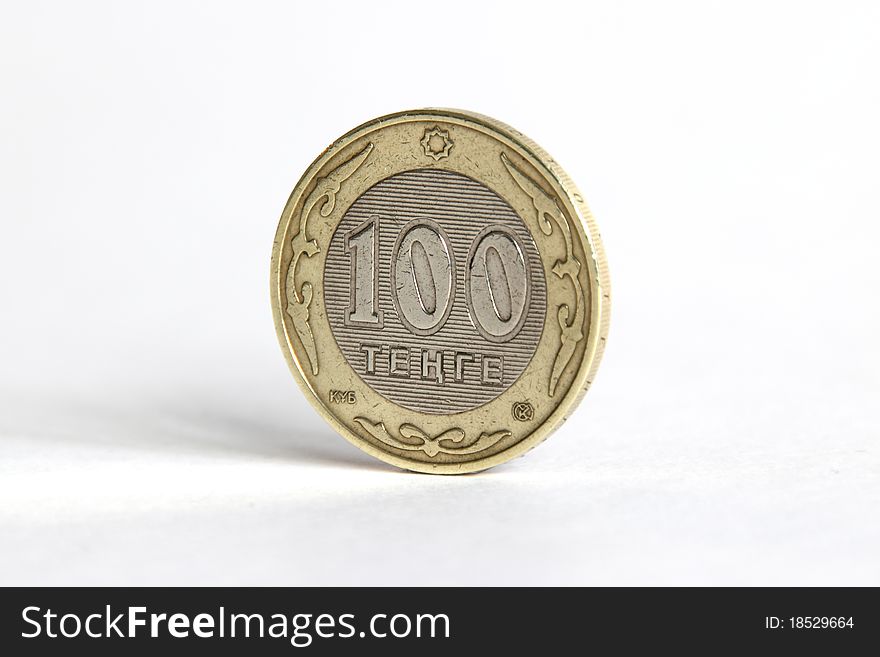 100 tenge stands on the edge on a white background
