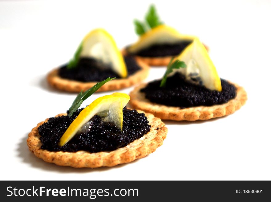 Picture of caviar , lemon and a green leaf on a biscuit. Picture of caviar , lemon and a green leaf on a biscuit