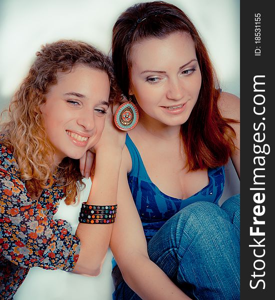A young girl leans on girl friend’s shoulder & both smile, on white background. A young girl leans on girl friend’s shoulder & both smile, on white background