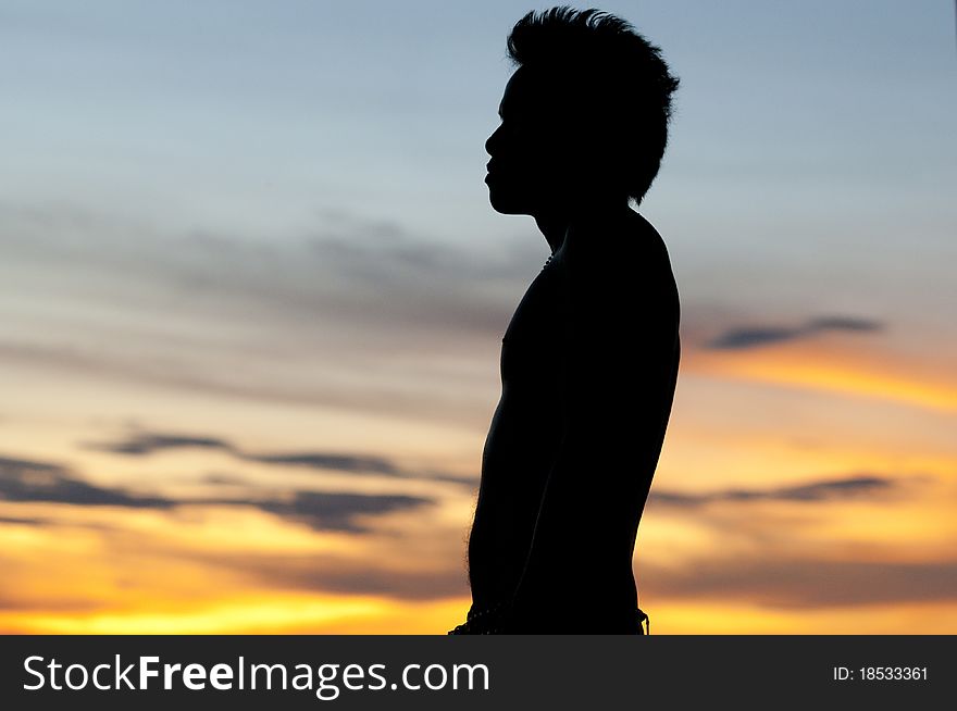 Asian male silouetted against sunset. Asian male silouetted against sunset