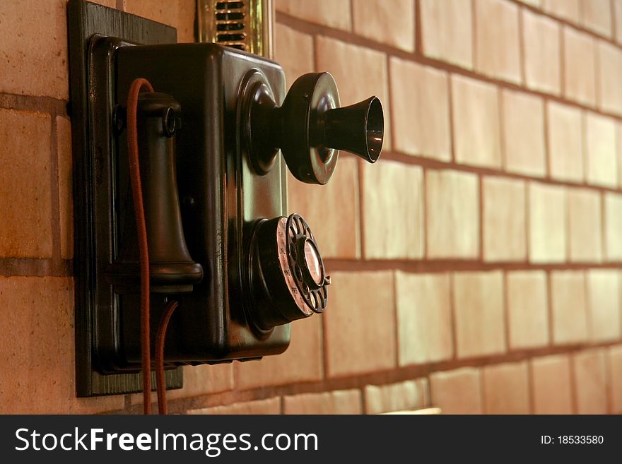 Old telephone mounted on a tiled wall in sepia. Old telephone mounted on a tiled wall in sepia