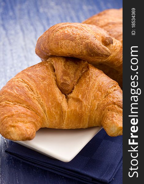 Photo of delicious fresh croissants for breakfast on a soft blue background. Photo of delicious fresh croissants for breakfast on a soft blue background