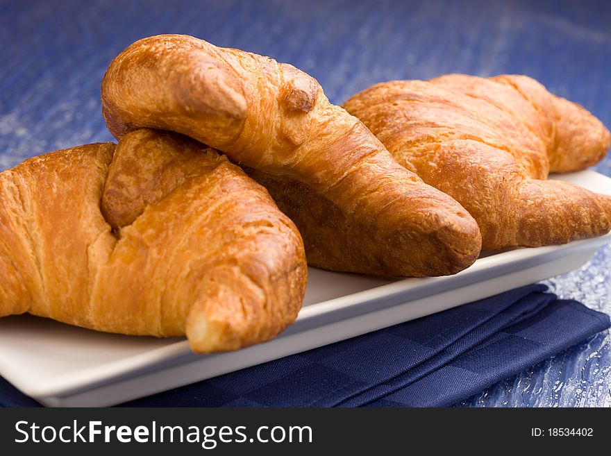 Photo of delicious fresh croissants for breakfast on a soft blue background. Photo of delicious fresh croissants for breakfast on a soft blue background