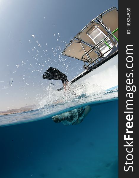 Scuba diver enters the water from a boat, Over under shot. Scuba diver enters the water from a boat, Over under shot.