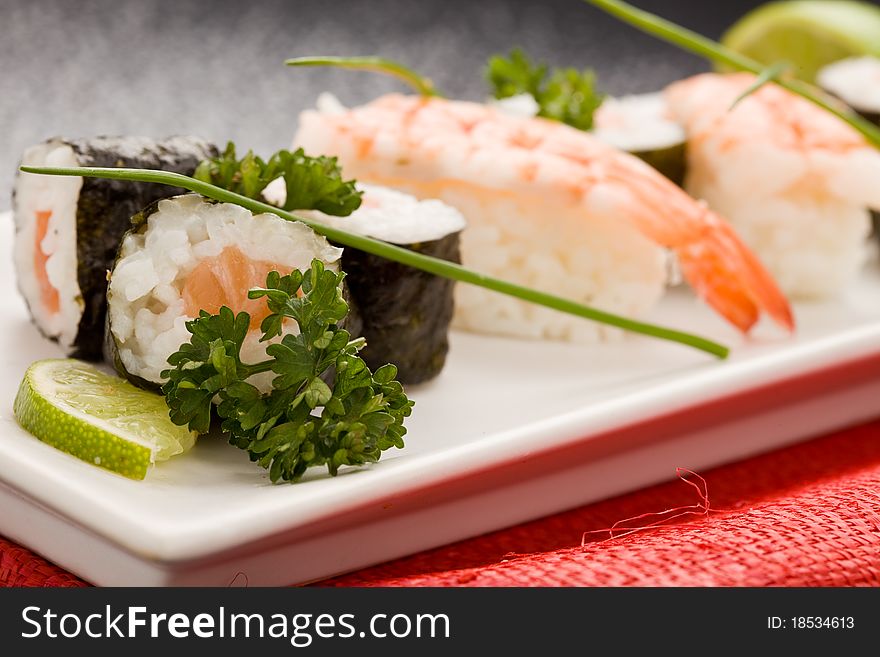 Photo of delicious sushi and sashimi food on rectangular plate with parley