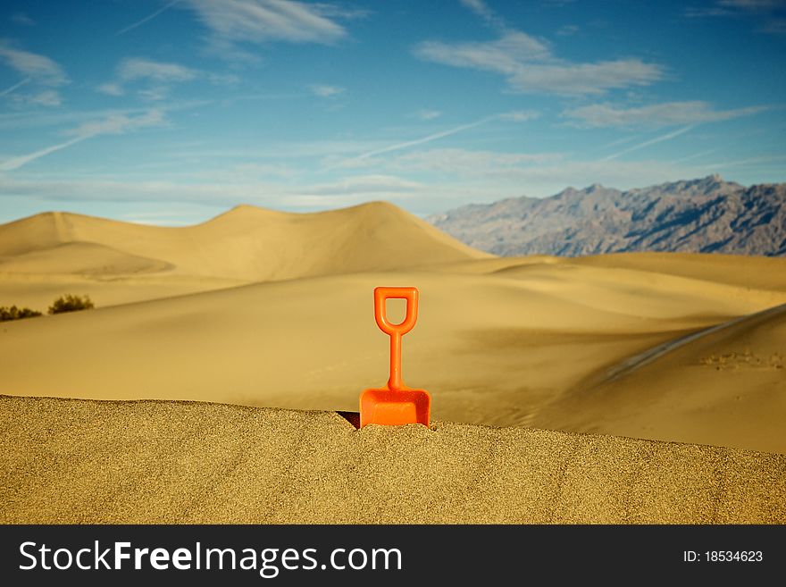 One single toy shovel stands against a sea of sand. One single toy shovel stands against a sea of sand.