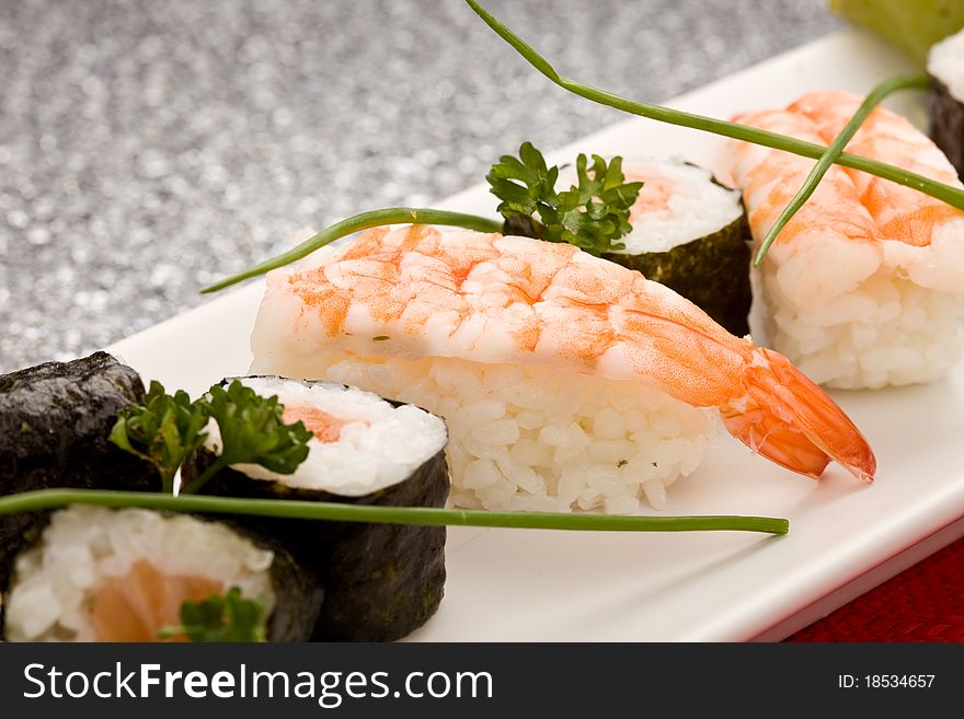 Photo of delicious sushi and sashimi food on rectangular plate with parley