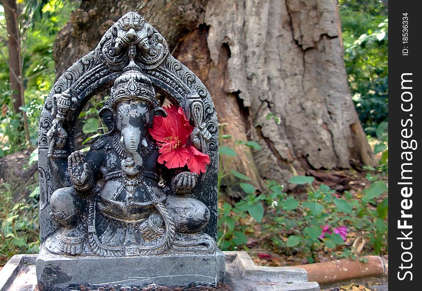 A stone ganesh deity out in the forest.