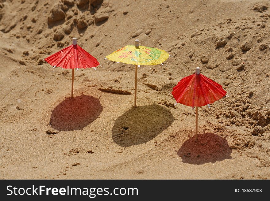 Three toy umbrella on sand. close-up. Three toy umbrella on sand. close-up.