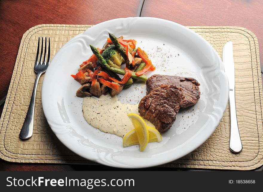 Grilled meat with sauce and vegetables on the plate