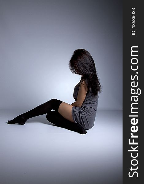 Beautiful sexual girl brunette posing on floor, gray background, studio shot