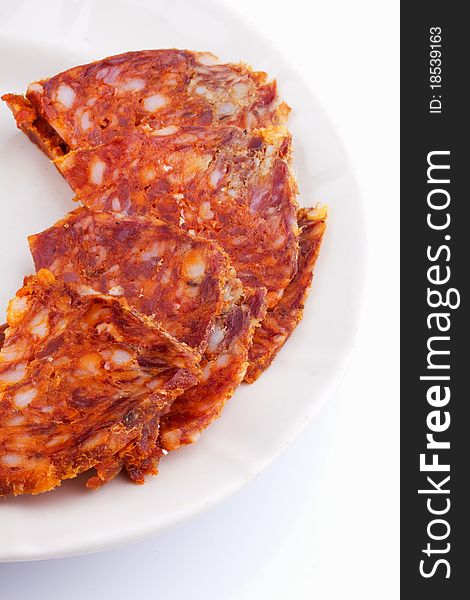 Raw thinly sliced sausage in a white bowl on a white background. Raw thinly sliced sausage in a white bowl on a white background