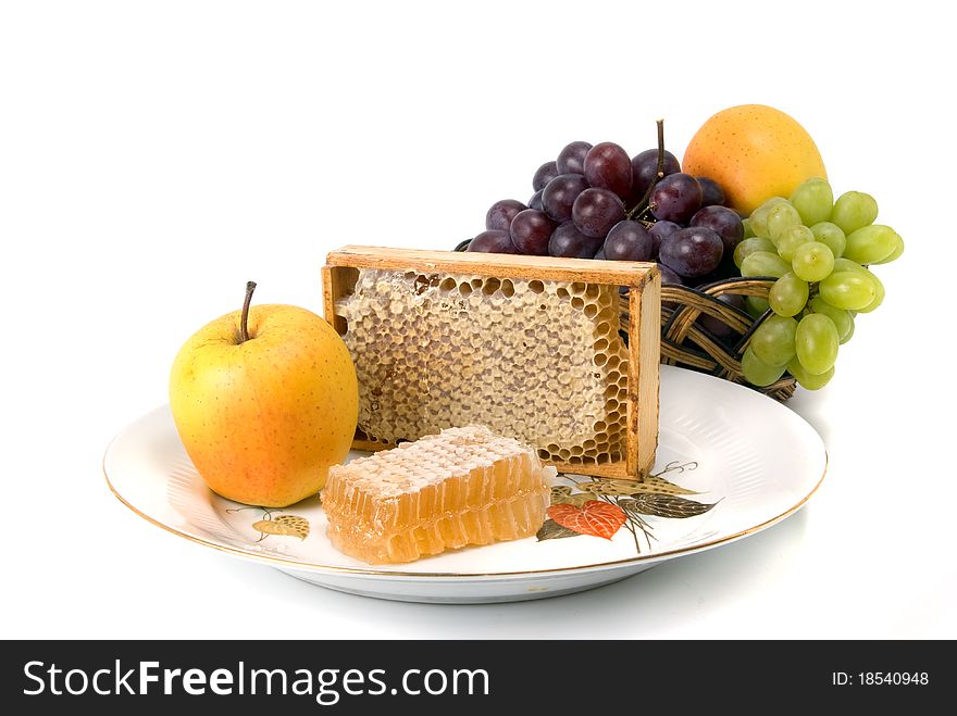 Honeycomb in border with fruits on dish